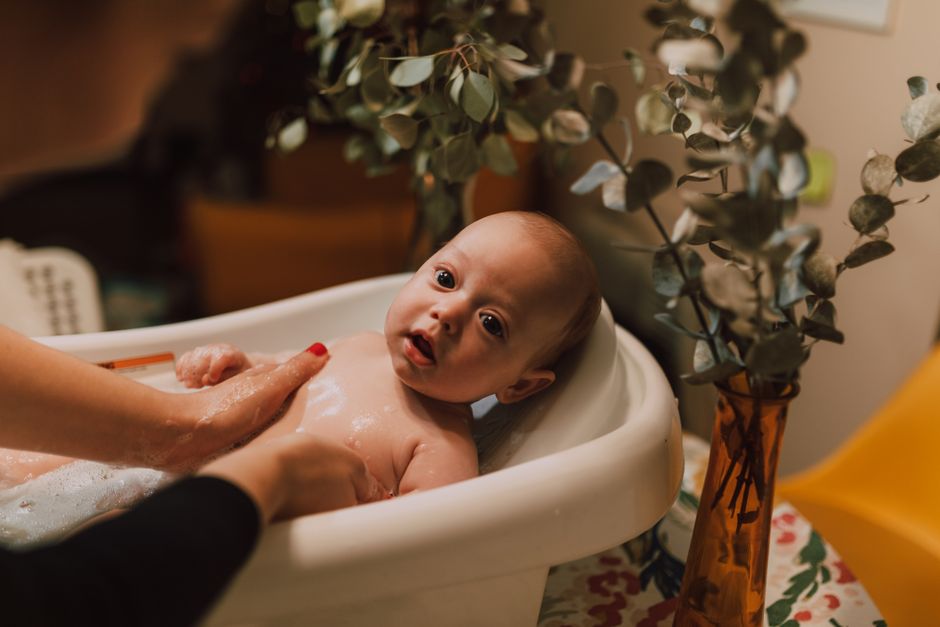 Bebek banyo rutini uygulayan ebeveynler güvenli bir banyo sırasında görüntüleniyor
