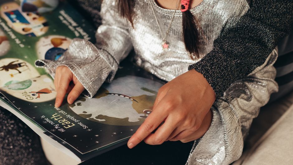 Bir ebeveyn, çocukla resimli kitap okuyor ve dil gelistiriyor