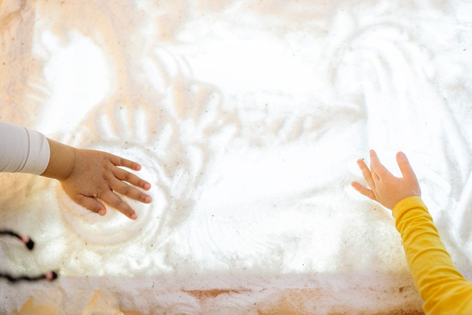 Child exploring different textures and objects in a supervised play area