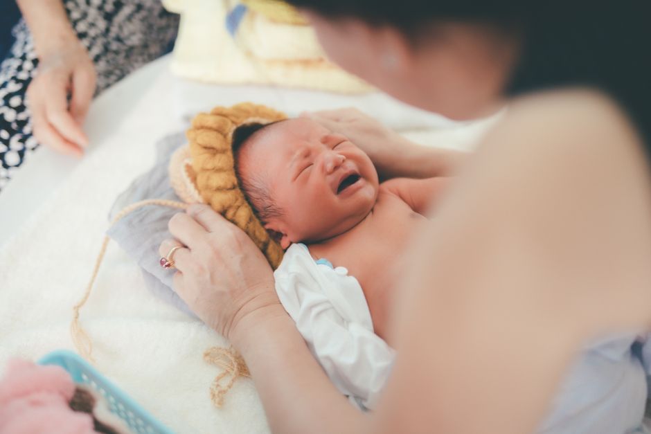 Bebek odasında ağlayan bebek ve yakındaki anne-baba sakinleşmeye çalışıyor.